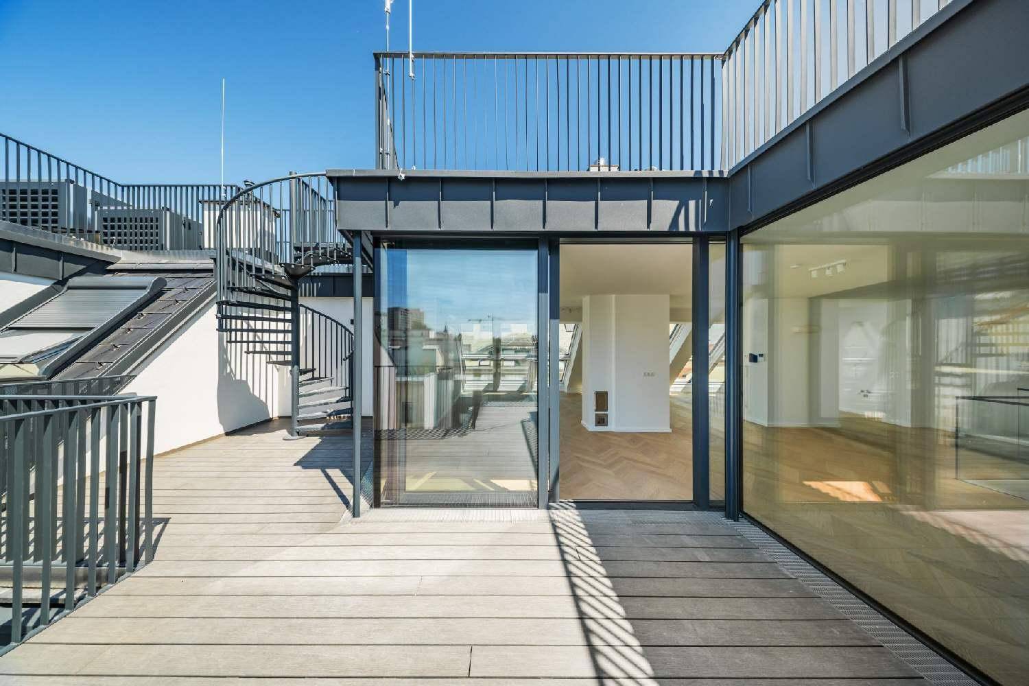 Geräumige Dachterrasse mit Holzbelag und einer eleganten Wendeltreppe zu einer weiteren Ebene.