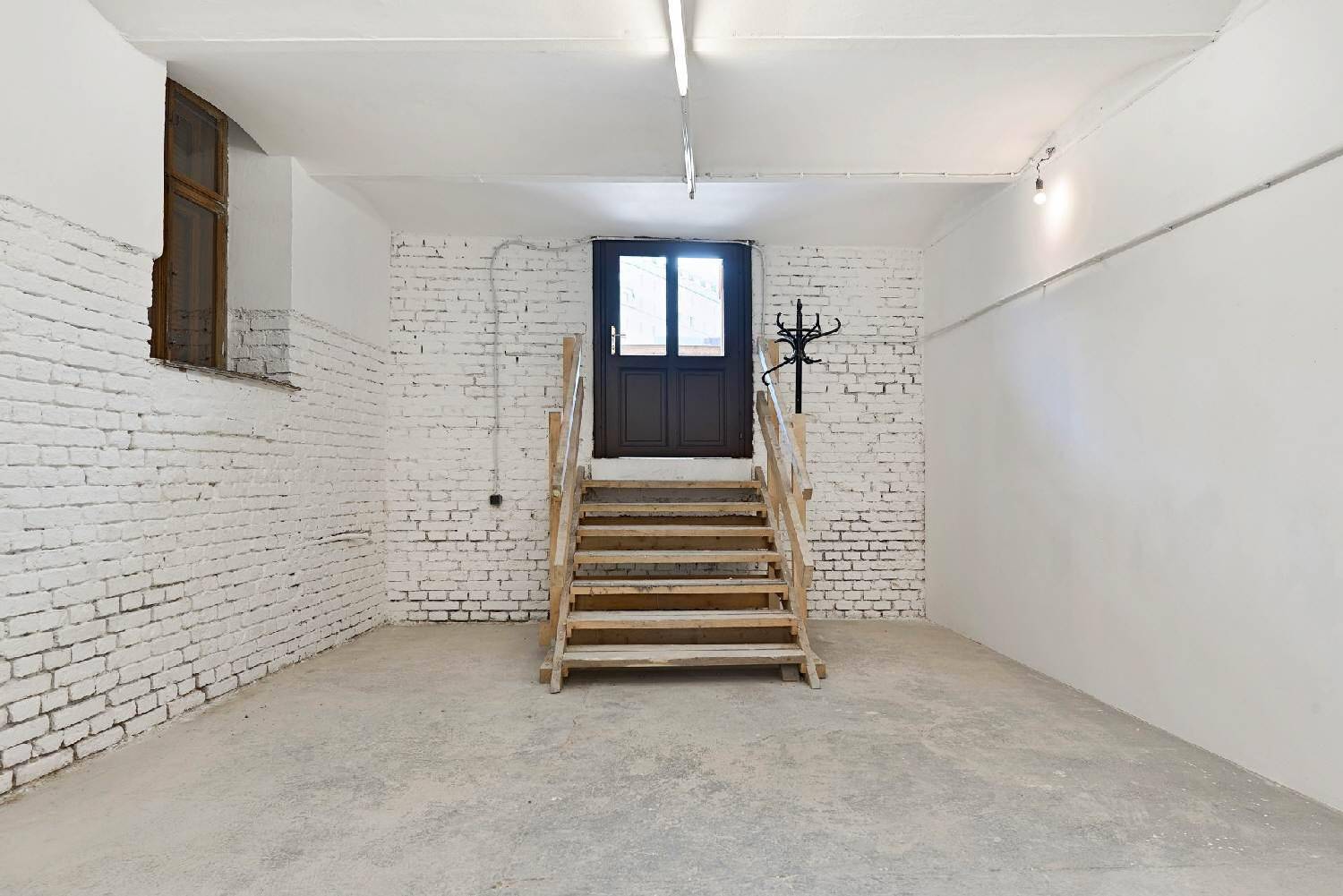 Lagerraum mit Holztreppe, dunkler Tür und Garderobe, ideal für vielseitige Nutzungsmöglichkeiten.
