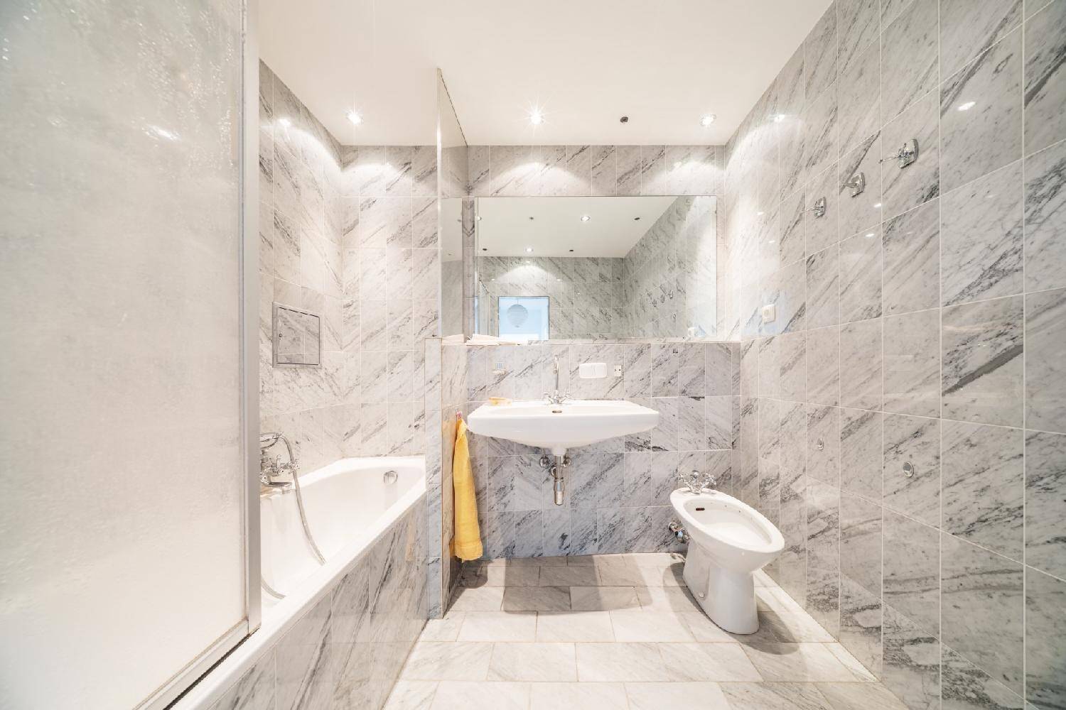 Elegantes Badezimmer mit Marmorfliesen, Badewanne, Waschbecken und Bidet.