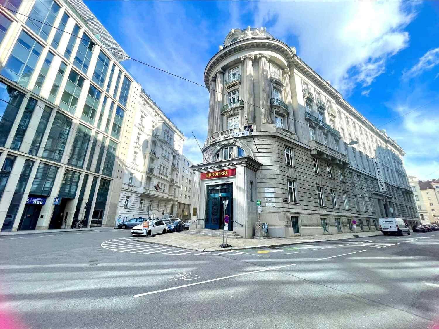 Historisches Eckgebäude mit klassischer Architektur und modernen Glasfassaden im städtischen Umfeld.
