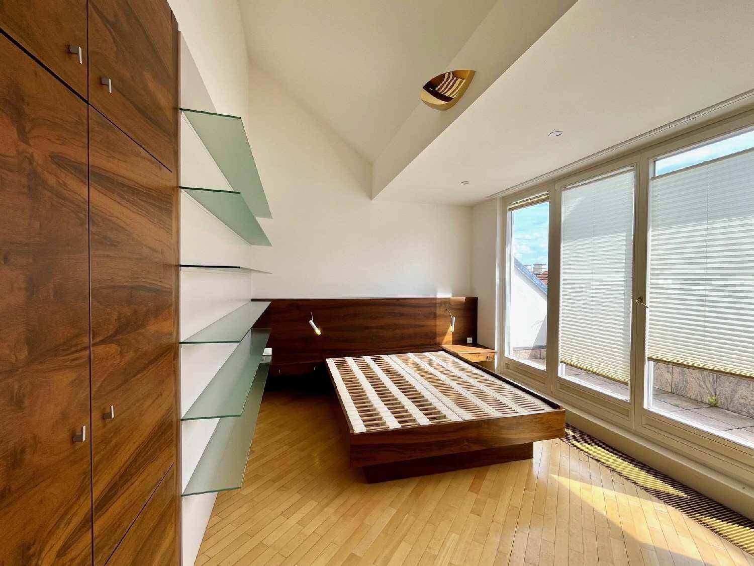 Helles Schlafzimmer mit Holzboden, großen Fenstern und Zugang zu einem Außenbereich.