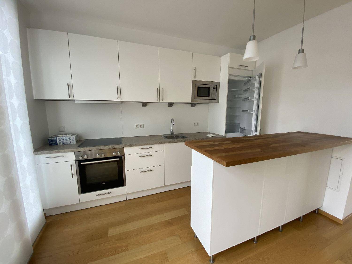 Detailansicht der modernen Einbauküche mit weißen Schränken, Holztheke und integrierten Geräten.