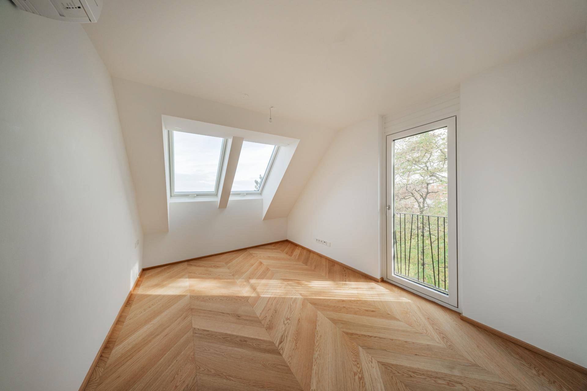 Gemütliches Zimmer im Dachgeschoss mit schrägen Wänden, Dachfenstern und französischem Balkon.