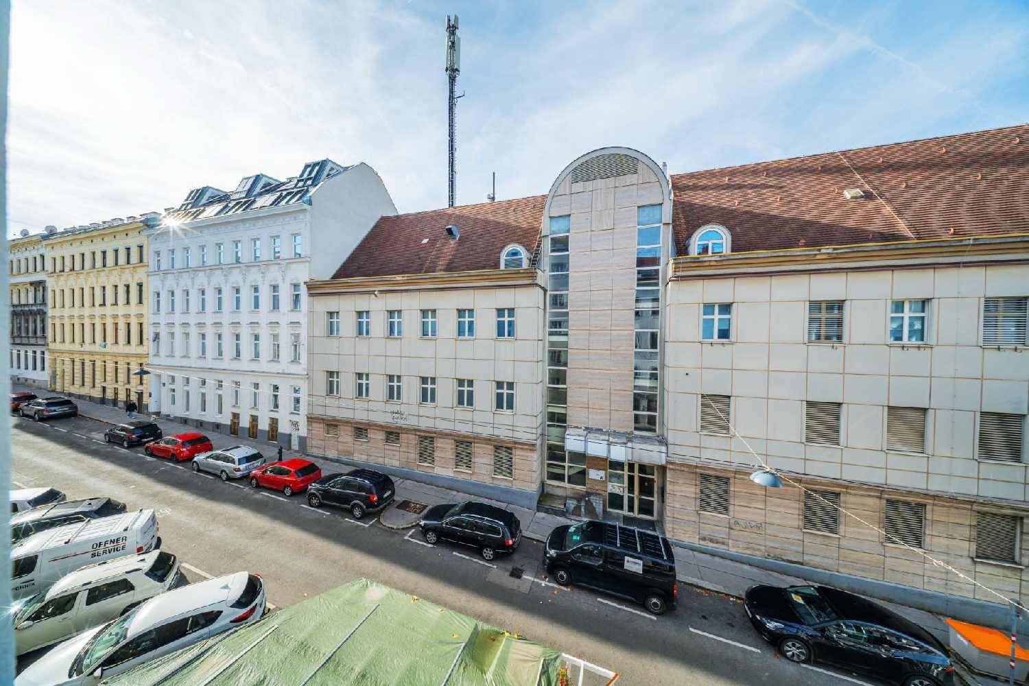 Blick von oben auf eine belebte Straße mit parkenden Autos und umliegenden Gebäuden.