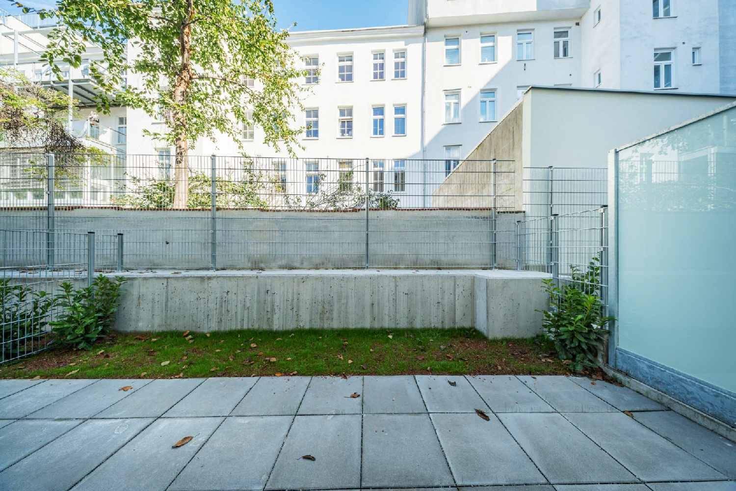 Kleiner, gepflegter Gartenbereich mit Terrasse und Blick auf das umliegende Gebäude.