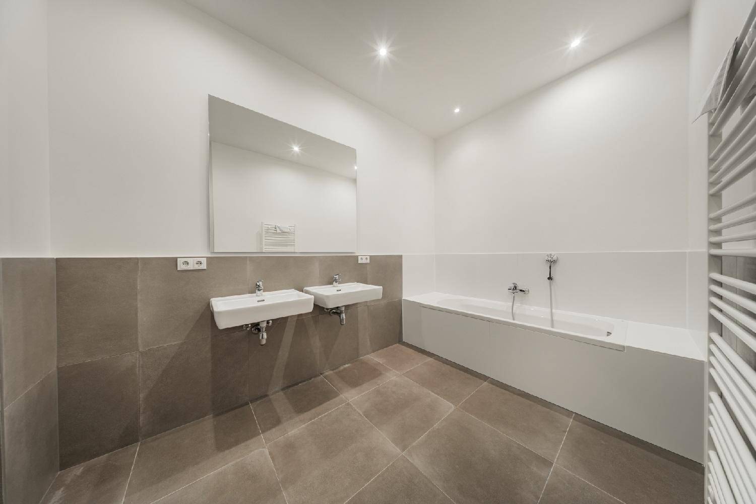 Modernes Badezimmer mit Doppelwaschbecken, Badewanne und beheiztem Handtuchhalter.