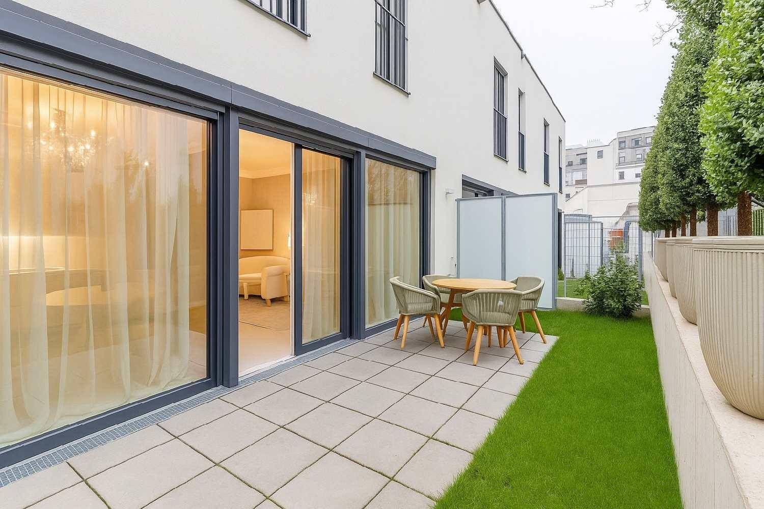 Moderne Terrasse mit Gartenbereich, Sitzgelegenheiten und großen Glasschiebetüren zum Innenraum.