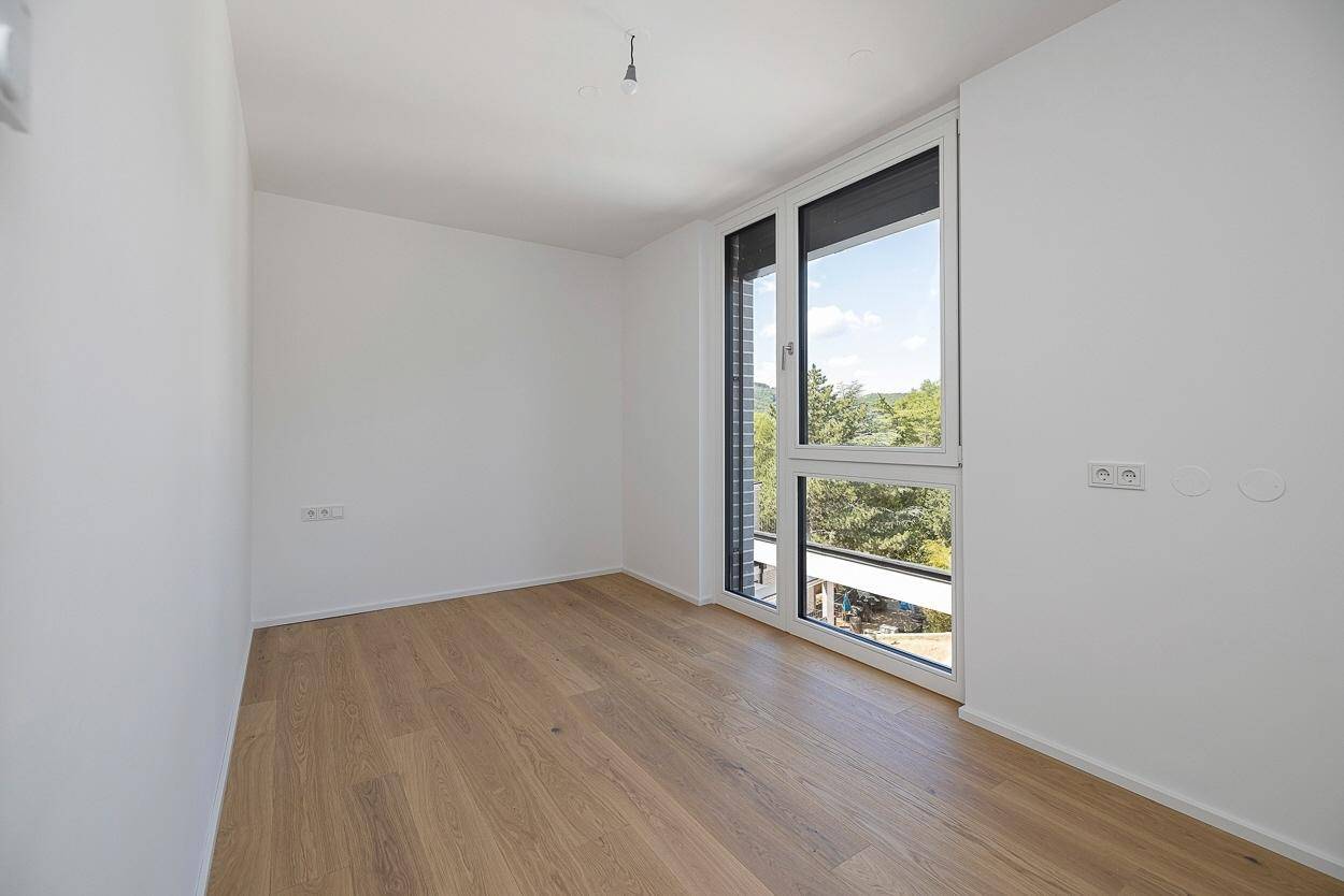 Geräumiges Schlafzimmer mit Holzboden und großen Fenstern, bietet viel Tageslicht.