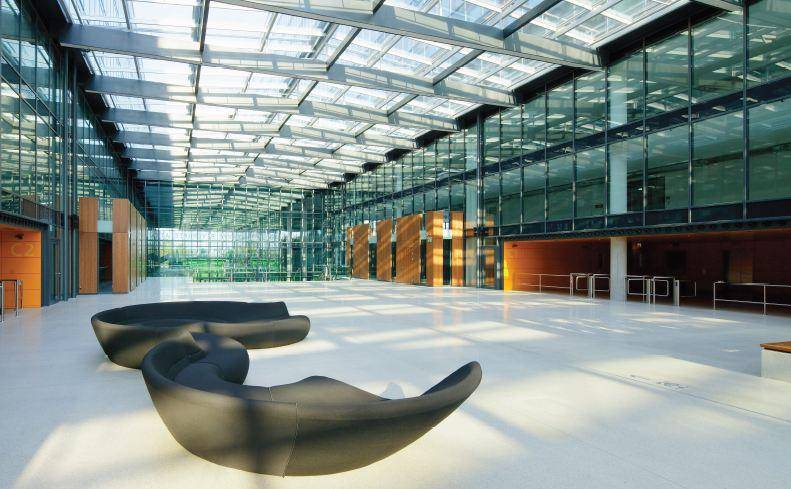 Großzügige, moderne Lobby mit Glasdach, viel Tageslicht und stilvollen Sitzgelegenheiten.