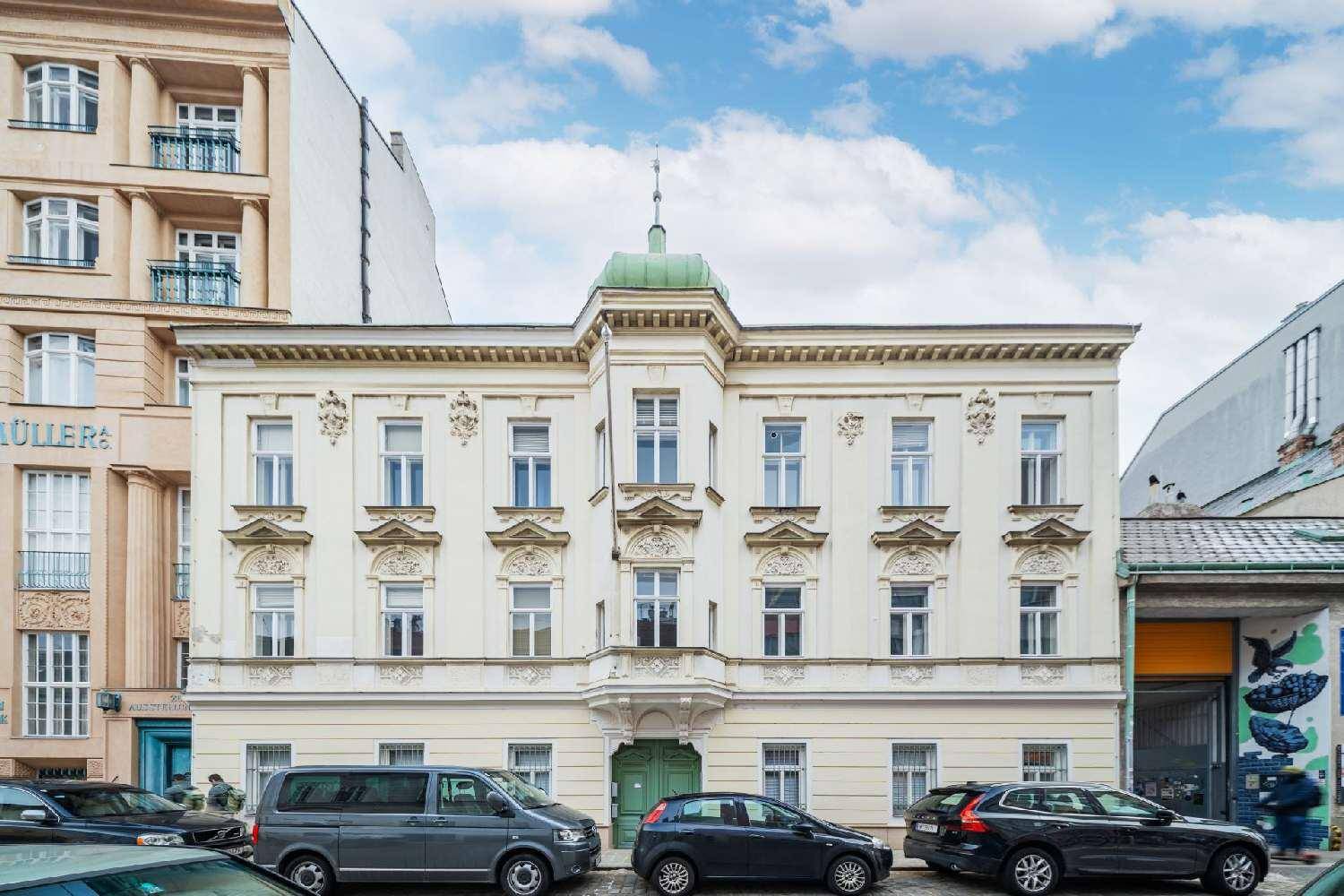 Historisches Gebäude mit klassischer Architektur, vielen Fenstern und einer grünen Kuppel.