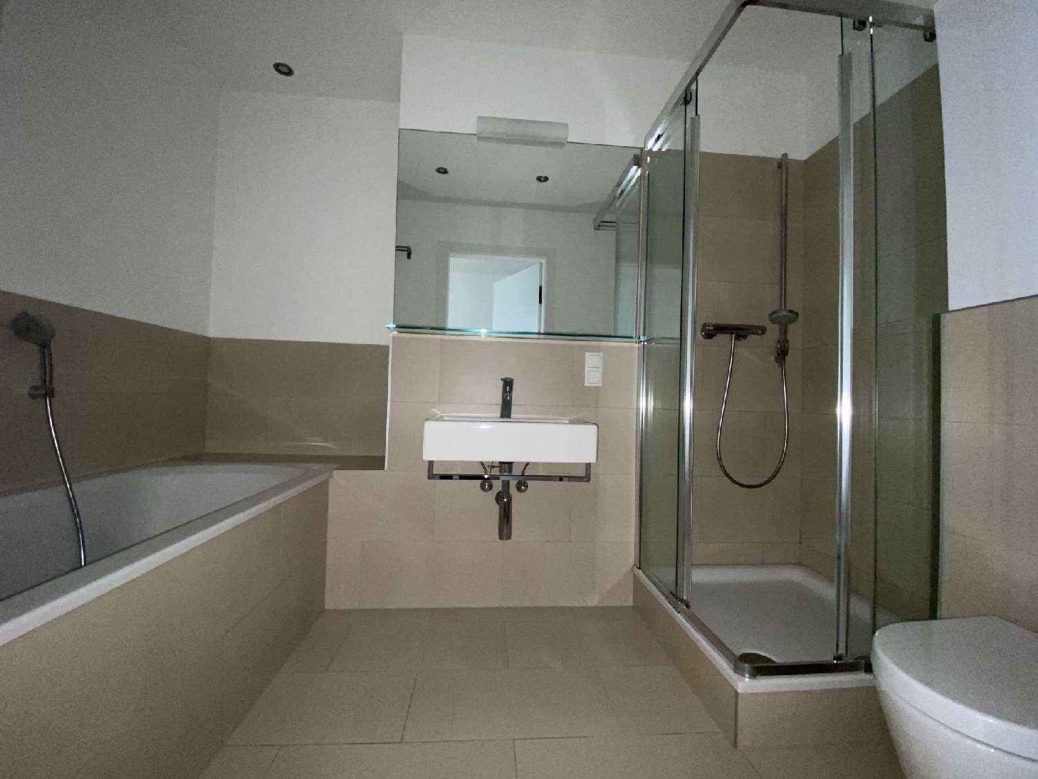 Modernes Badezimmer mit Badewanne, Duschkabine, Wandspiegel und beigefarbenen Fliesen.