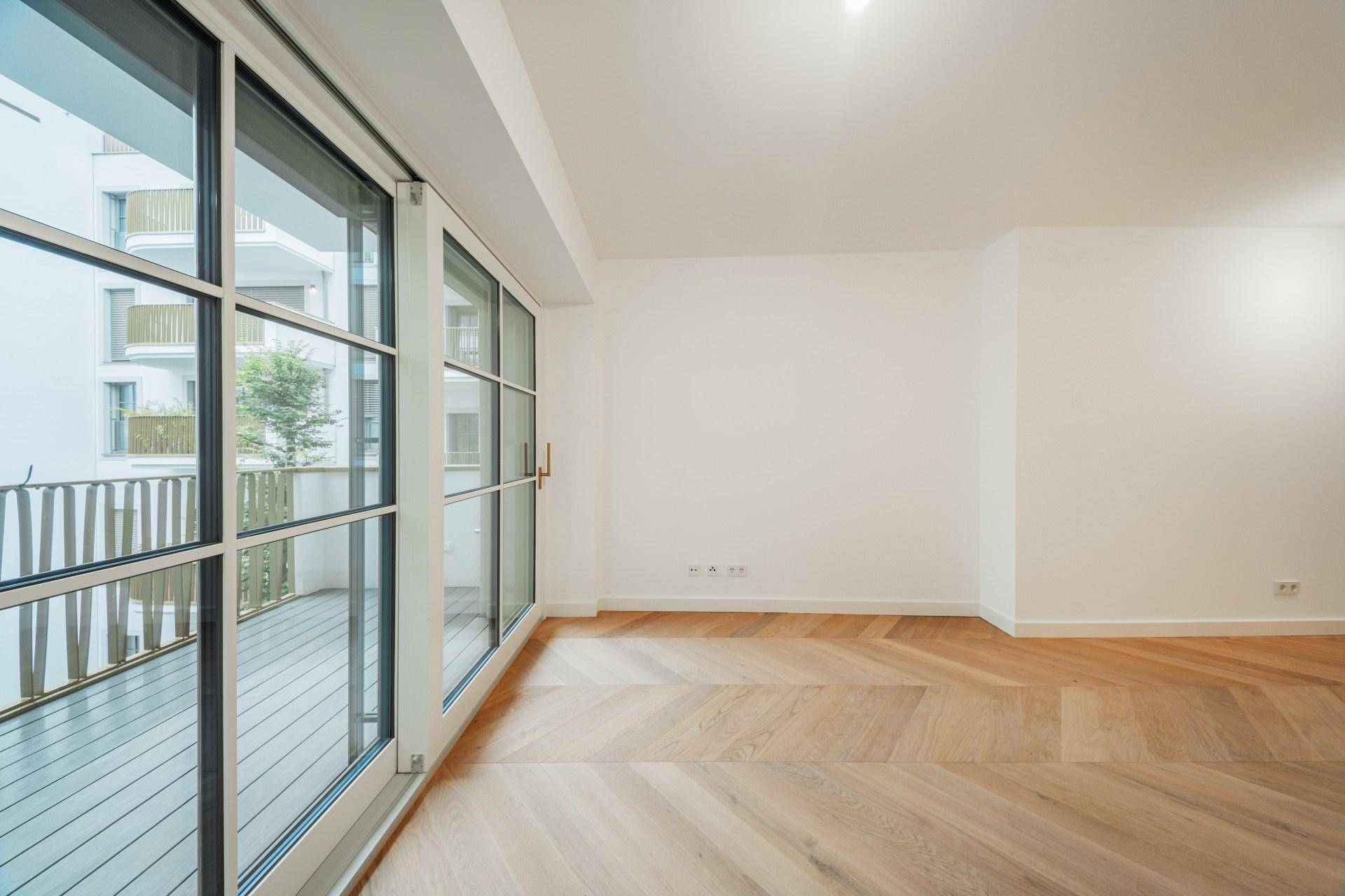 Große Fensterfront mit Zugang zum Balkon, die viel Tageslicht in den Raum lässt.