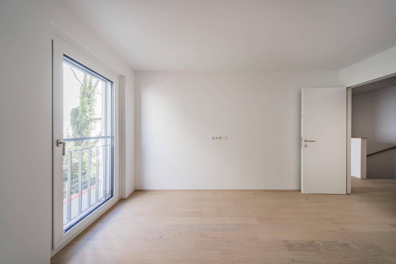 Helles Zimmer mit Parkettboden und bodentiefem Fenster mit französischem Balkon.