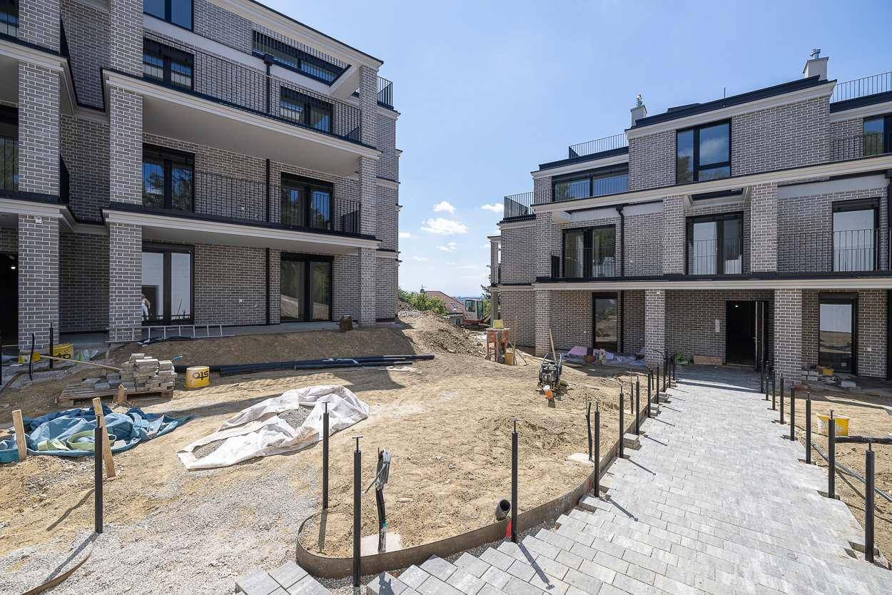 Neubauwohnungen mit moderner Ziegelfassade und im Bau befindlicher Außenanlage.