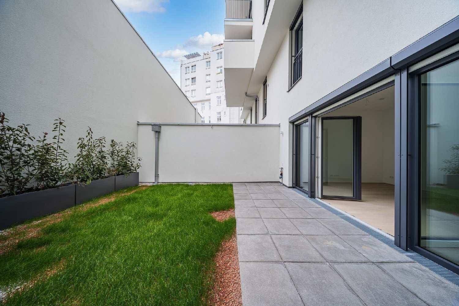 Kleiner privater Gartenbereich mit gepflasterter Terrasse und Rasenfläche direkt am Gebäude.