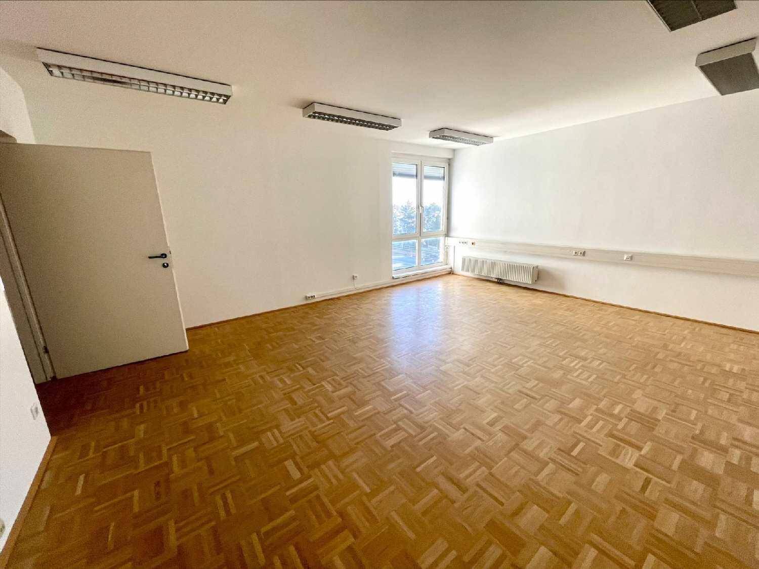 Heller Büroraum mit Parkettboden und einem großen Fenster, das den Raum gut belichtet und einladend wirkt.