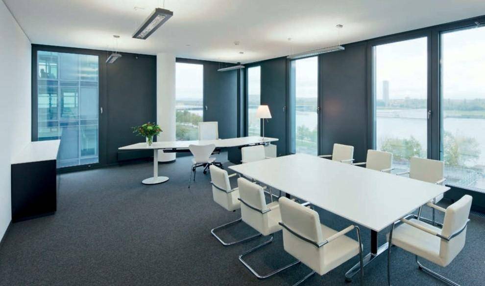 Moderner Konferenzraum mit großen Fenstern, Teppichboden und einem weiten Blick auf die Stadt und das Wasser.