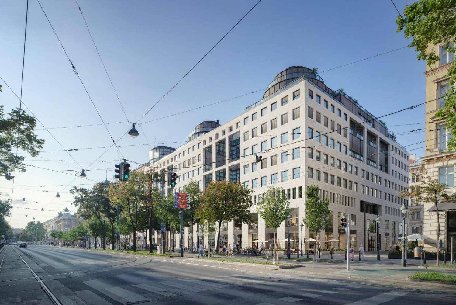 Moderne Gebäudefassade am Tag mit großen Fenstern, umgeben von Bäumen und einer belebten Straße.