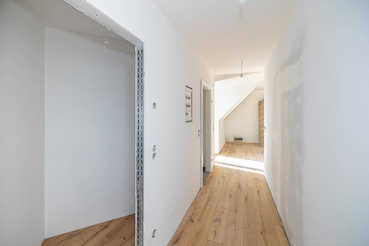 Langer, heller Flur mit Holzboden und Zugang zu mehreren Räumen im Dachgeschoss.