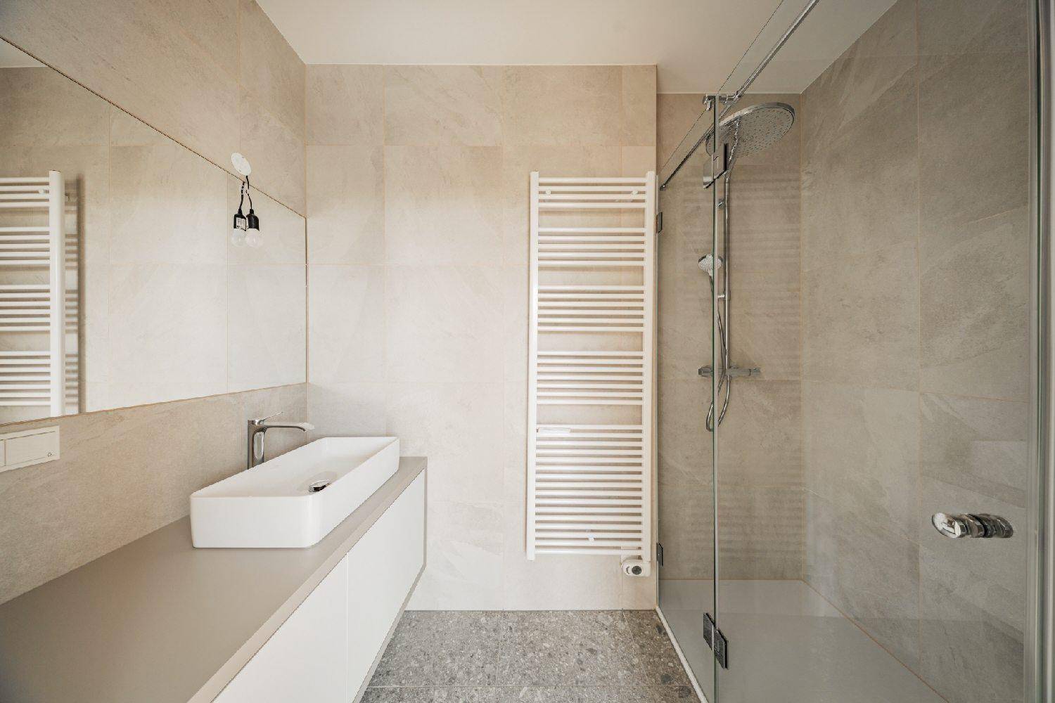Elegantes Badezimmer mit großer Dusche, modernem Waschtisch und beheiztem Handtuchhalter.