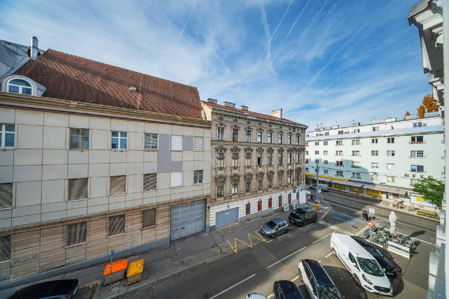 Blick von oben auf eine belebte Stadtstraße mit parkenden Autos und umliegenden Gebäuden.