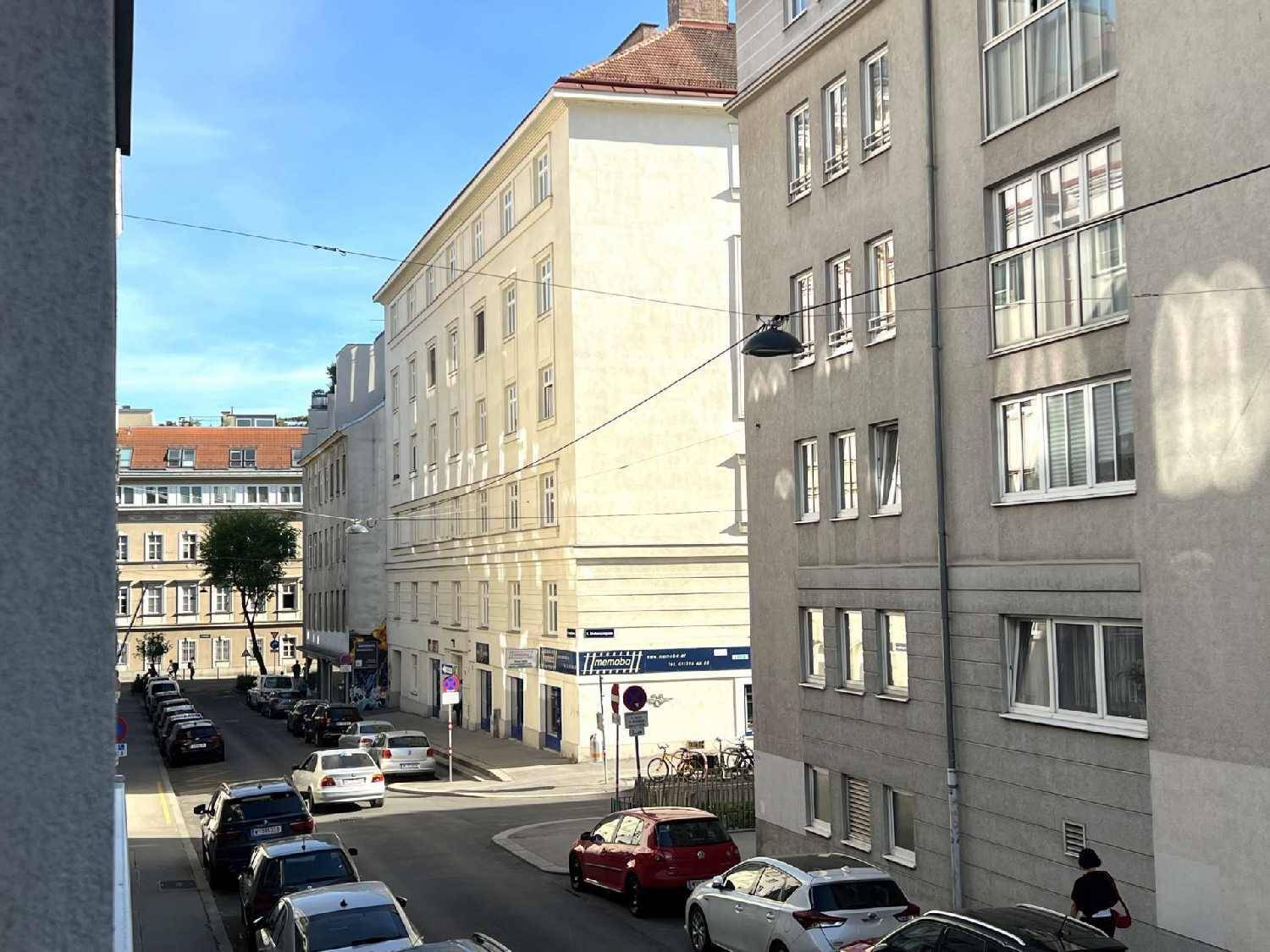 Blick aus dem Fenster auf eine belebte Stadtstraße mit parkenden Autos und historischen Gebäuden.