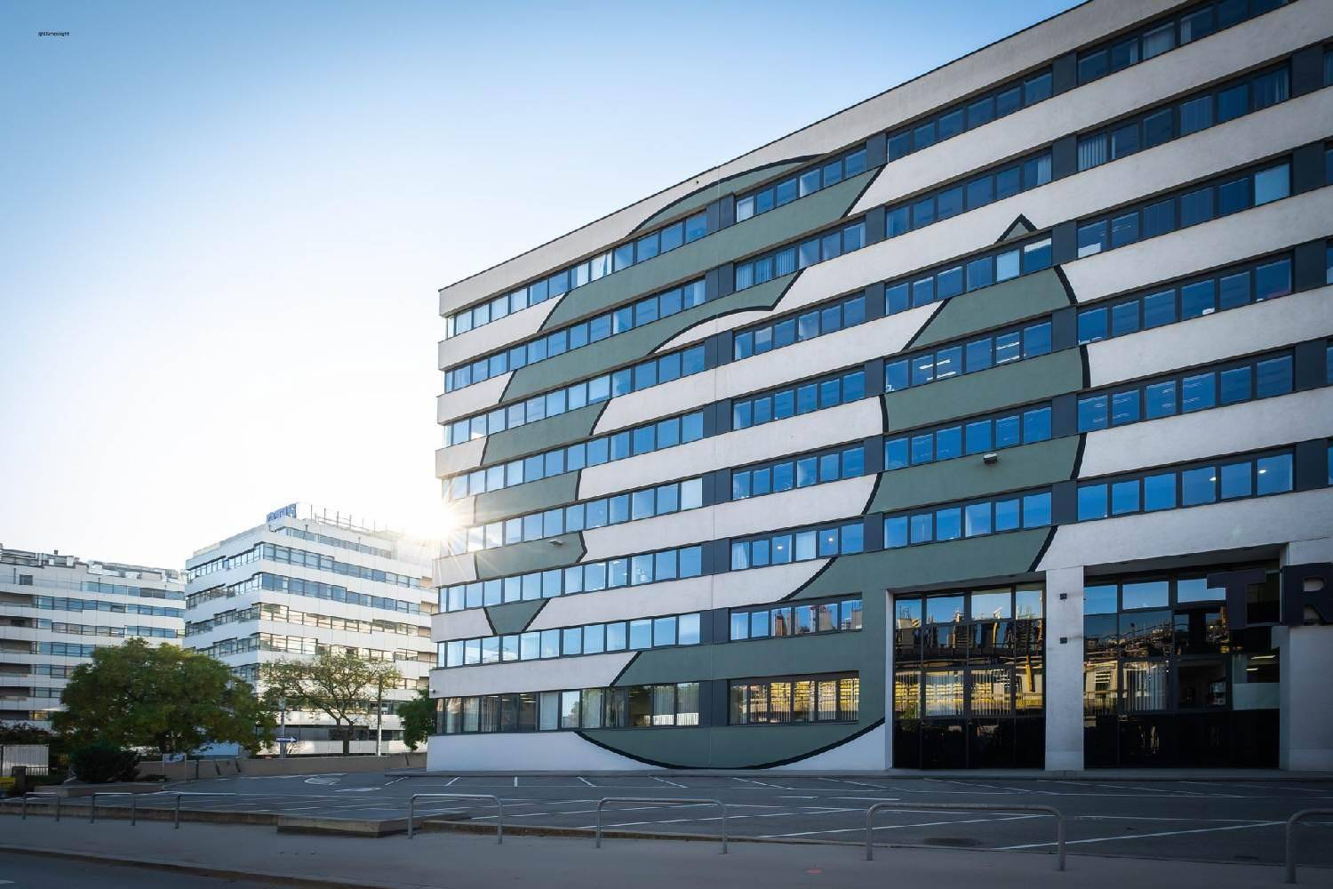 Moderne Bürogebäude-Fassade mit markantem Design, großen Fenstern und viel Tageslicht.