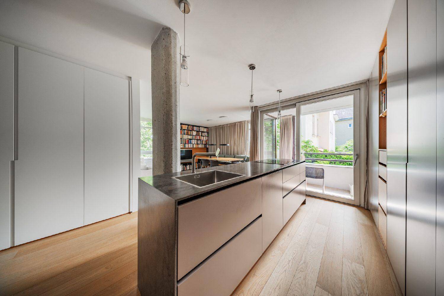 Elegante Küche mit minimalistischen Schränken, dunkler Arbeitsplatte und Holzboden.