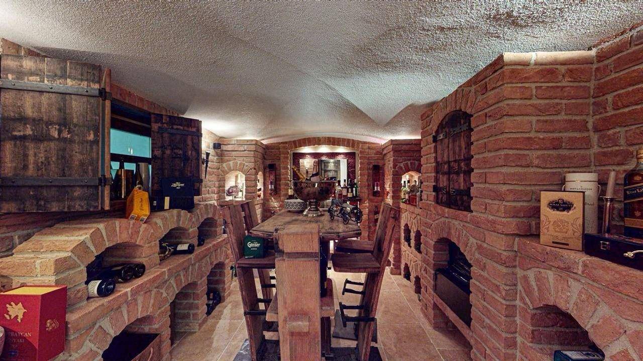 Rustikaler Weinkeller mit Ziegelgewölben, Holztisch und Weinregalen.