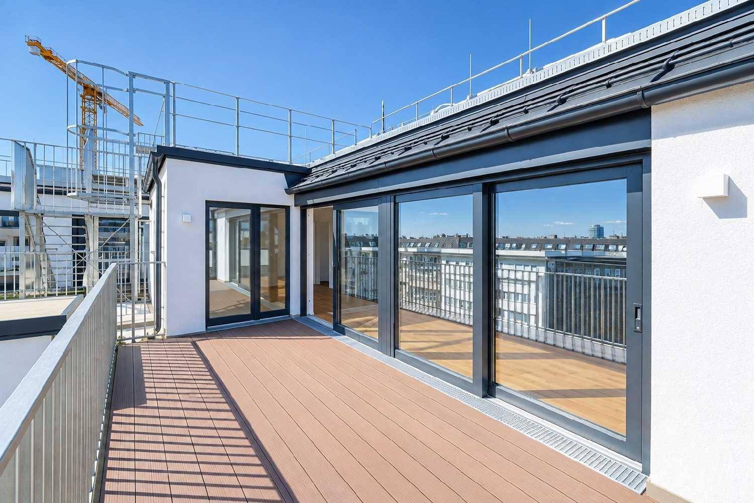 Große Dachterrasse mit Holzboden und Blick über die Stadt, umgeben von einer modernen Balustrade.
