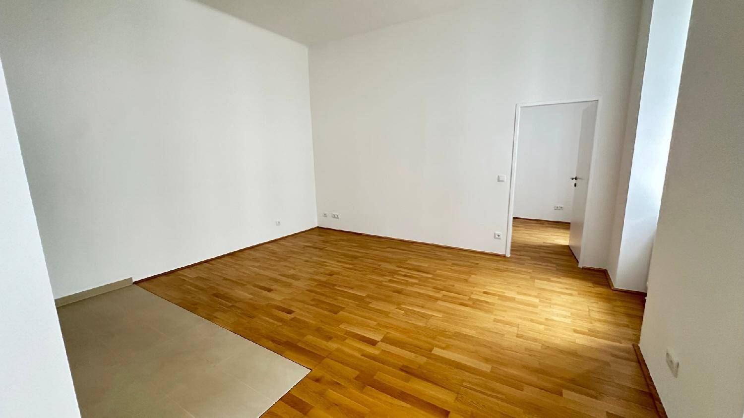 Leerer, heller Raum mit Parkettboden und weißen Wänden, bietet viel Gestaltungspotenzial für neue Bewohner.