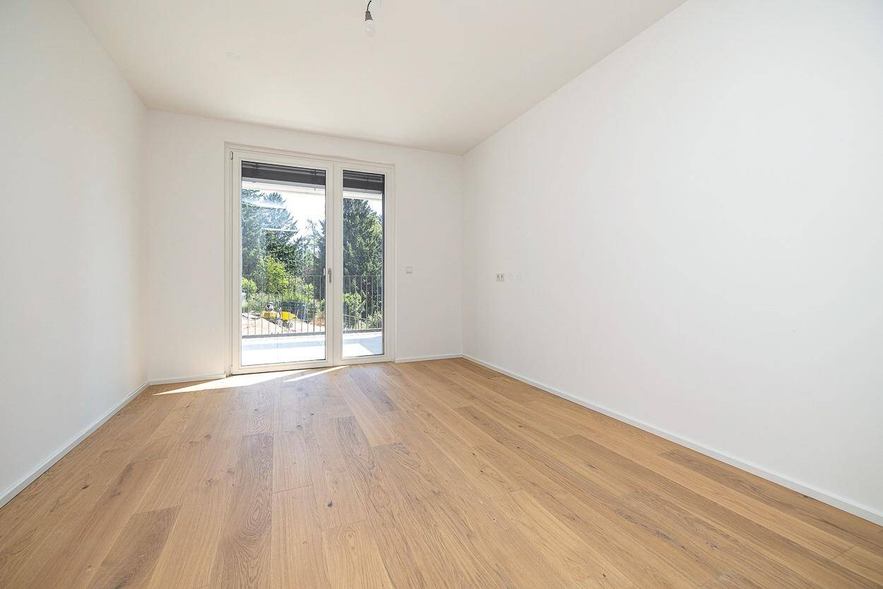 Helles Schlafzimmer mit Parkettboden und direktem Zugang zu einem Balkon.