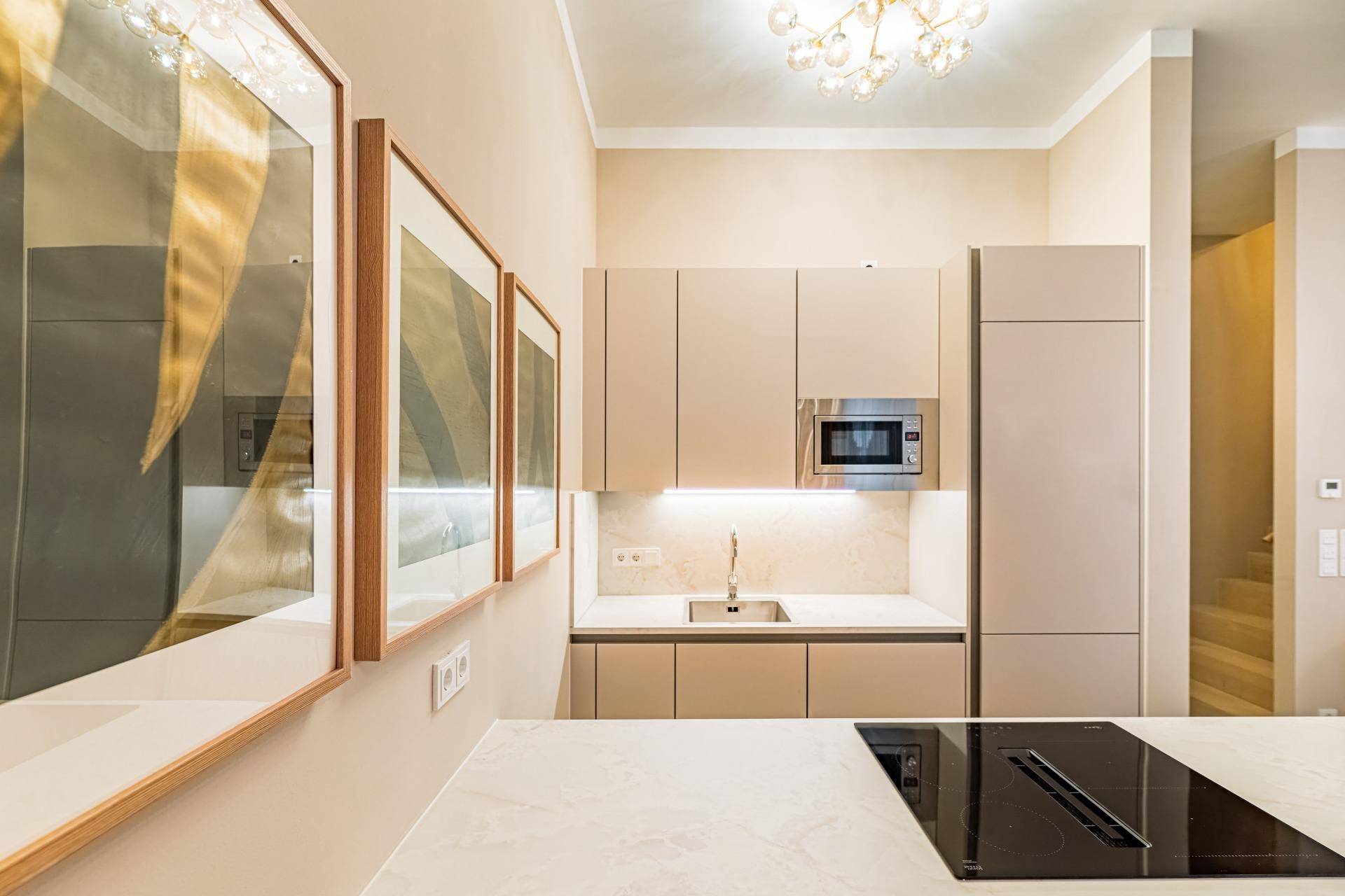 Stilvolle Einbauküche in Beige mit integrierter Mikrowelle und Spülbecken, ergänzt durch moderne Kunstwerke.