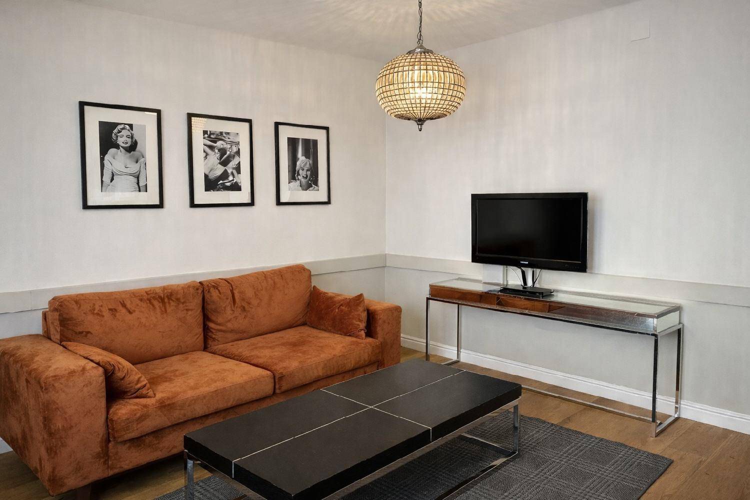 Wohnzimmer mit bequemer Couch, Couchtisch und einem Fernseher auf einem modernen Sideboard.