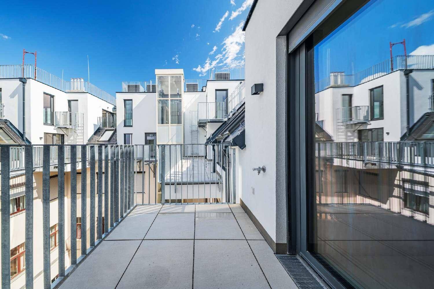 Geräumiger Balkon mit Fliesenboden und Blick auf die moderne Architektur der Nachbargebäude.