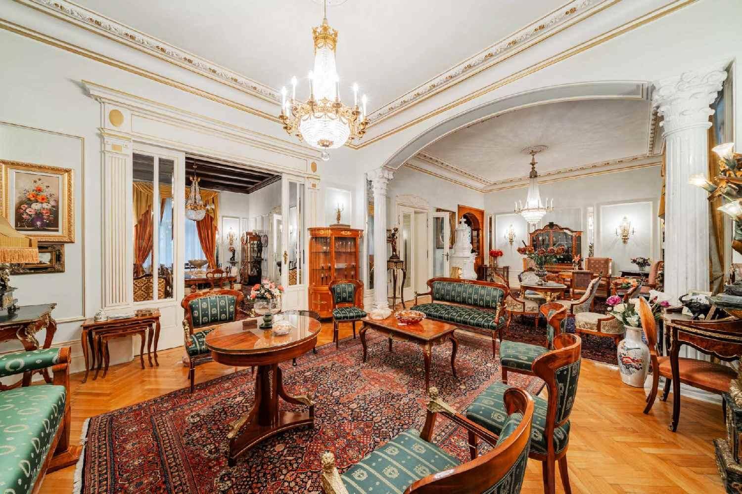 Weitläufiges Wohnzimmer mit mehreren Sitzbereichen, hohen Decken und klassischer Einrichtung.