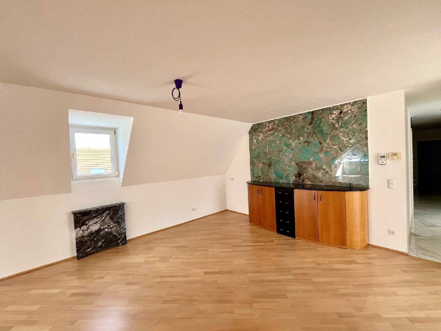 Heller Raum mit Holzboden, Dachschräge und dekorativer Wandverkleidung, ideal als Schlaf- oder Arbeitszimmer.