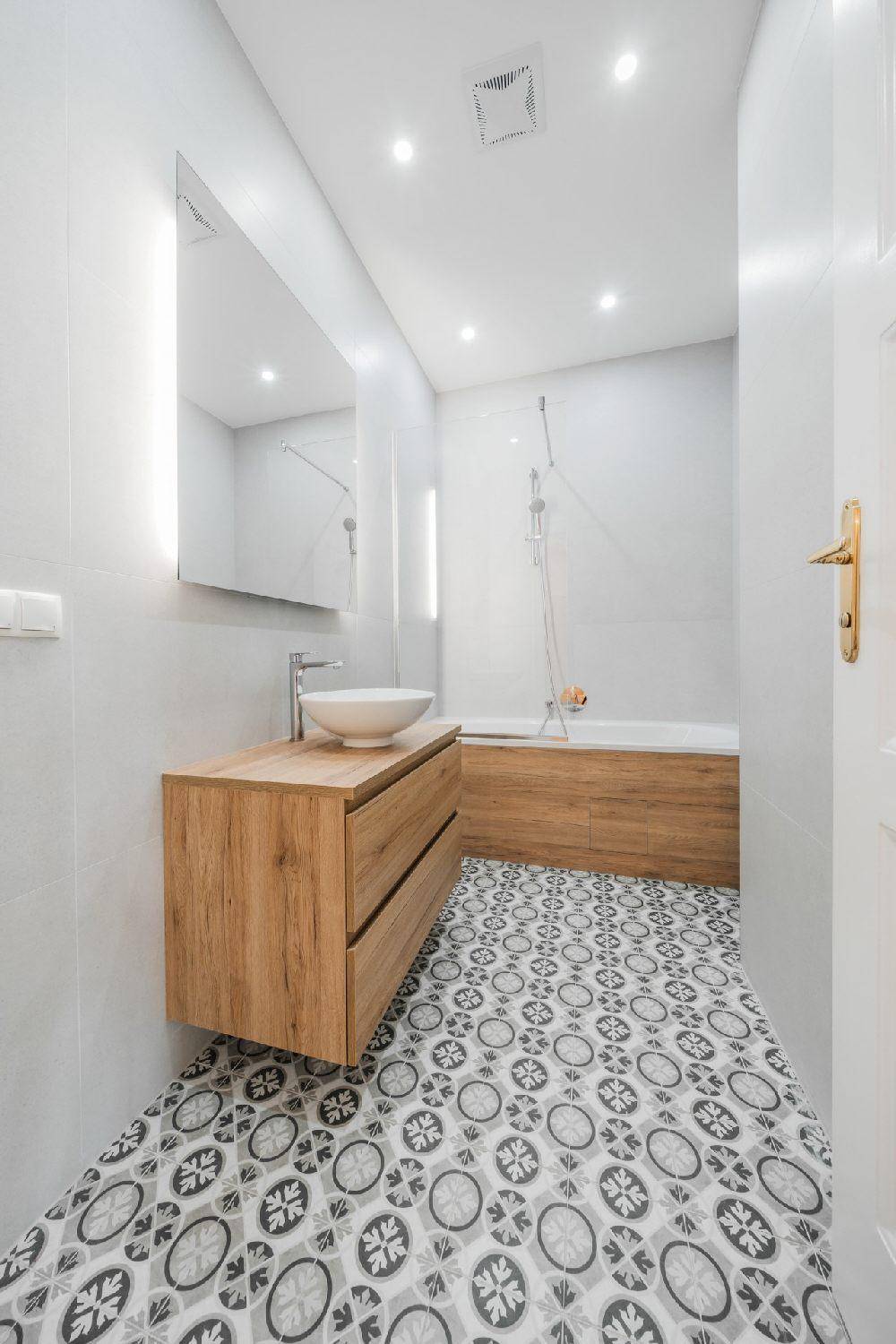 Modernes Badezimmer mit Holzelementen, Aufsatzwaschbecken und gemusterten Bodenfliesen.