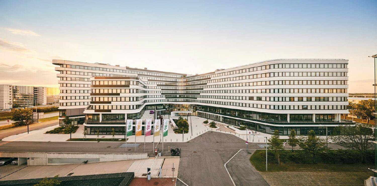 Moderne Bürogebäude-Architektur mit geschwungenen Linien und vielen Fenstern in einer weitläufigen Anlage.