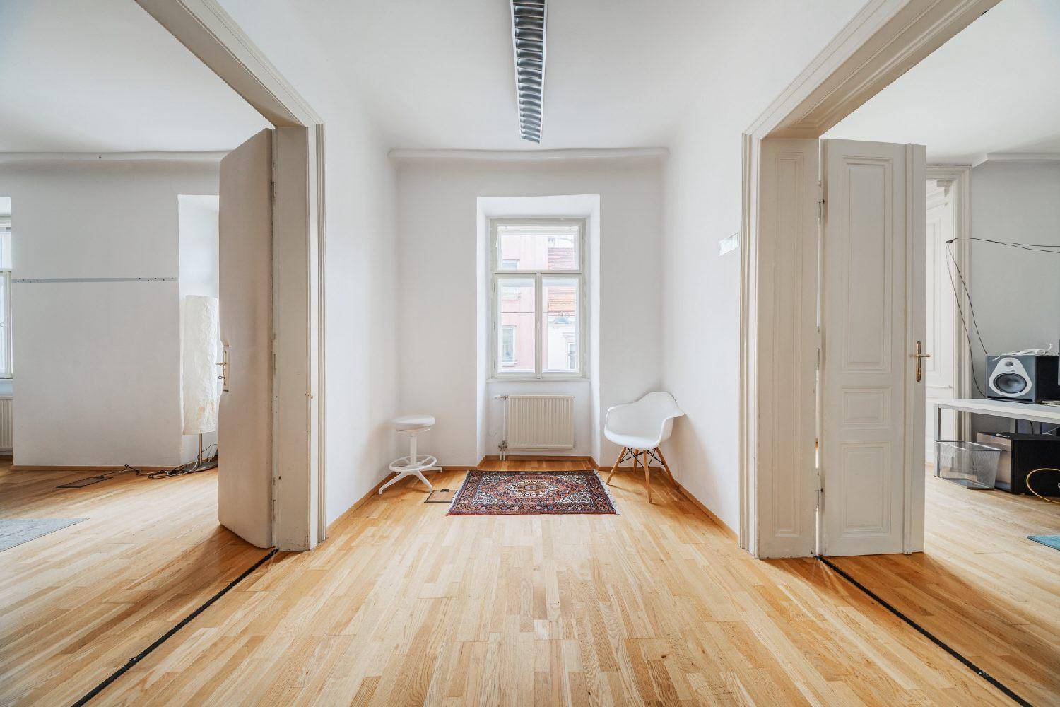 Heller, leerer Büroraum mit Holzboden, hohen Decken und großen Fenstern, bereit zur Einrichtung.
