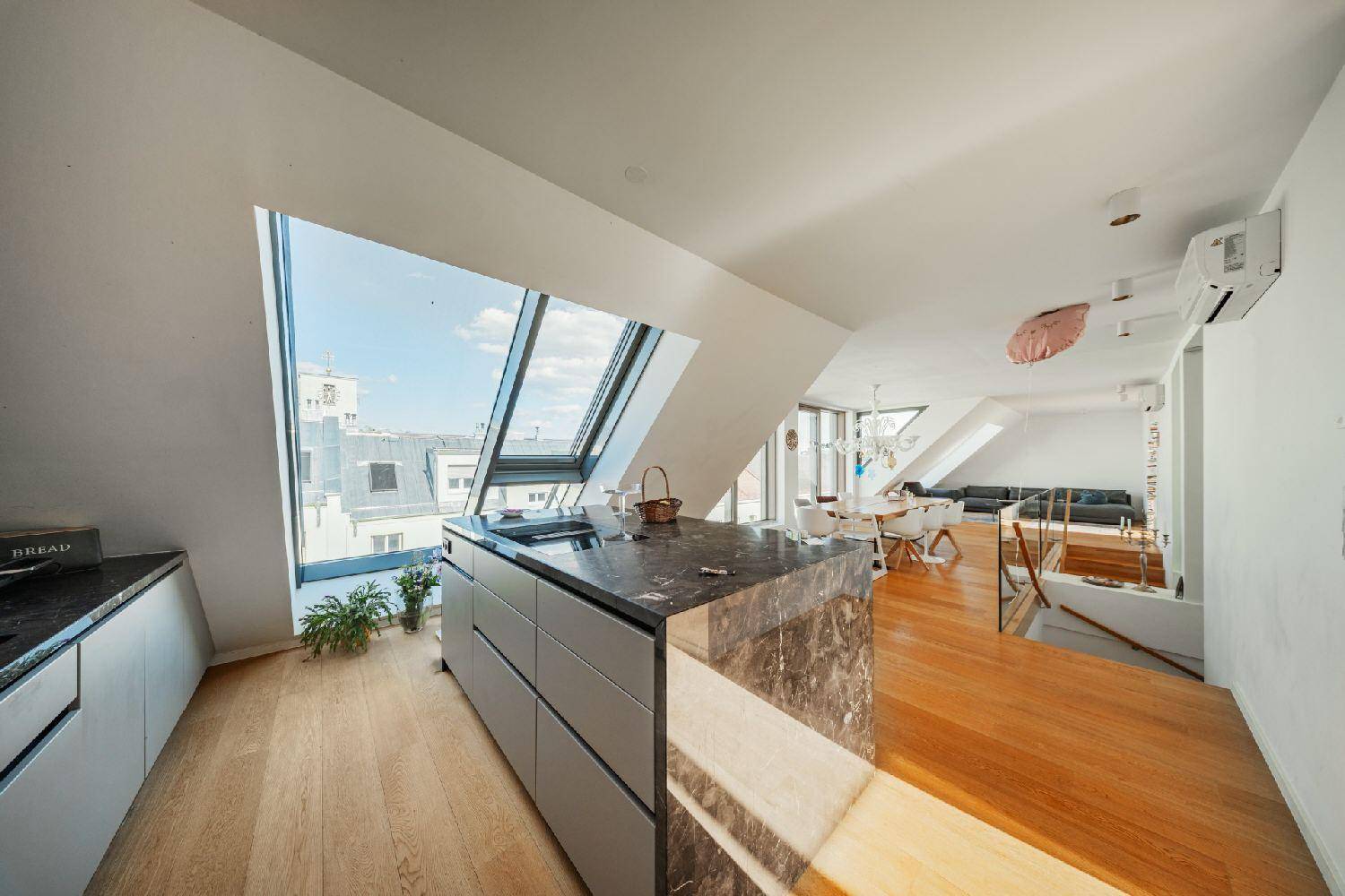 Moderne Küche mit Kücheninsel aus Marmor und Dachfenstern, die viel Tageslicht hereinlassen.