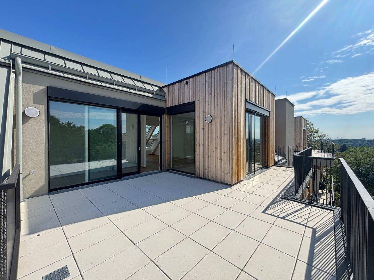 Weitläufige Dachterrasse mit moderner Holzfassade, großen Glasfronten und Panoramablick ins Grüne.