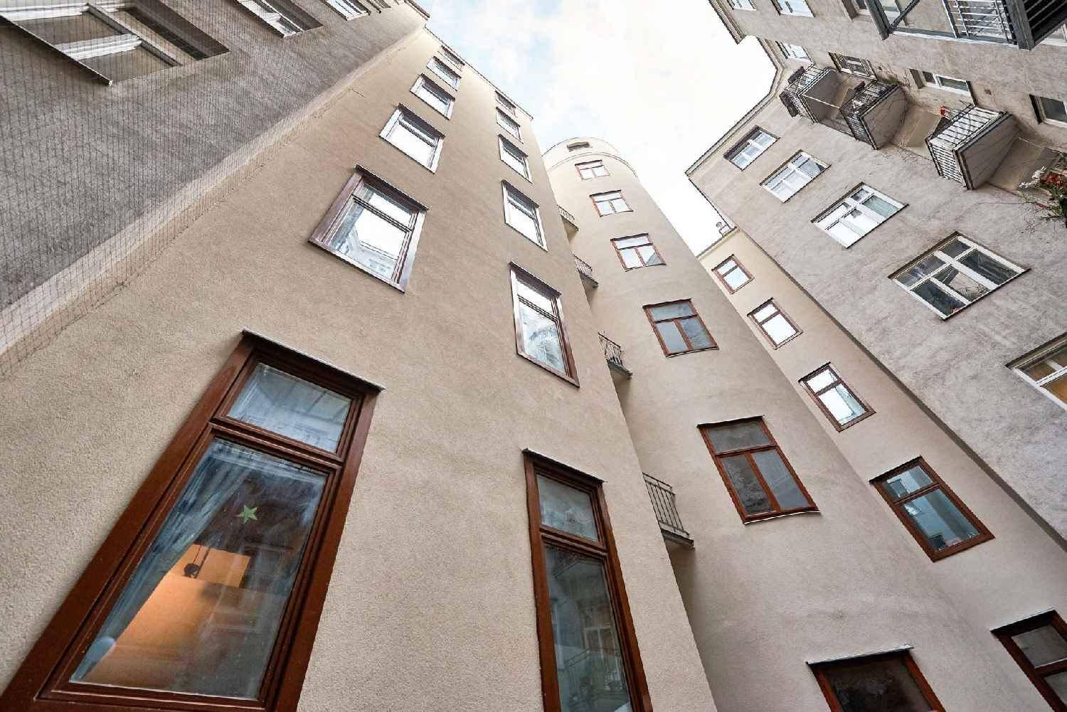 Blick auf die Fassade eines Altbaus im Innenhof mit vielen Fenstern und kleinen Balkonen.