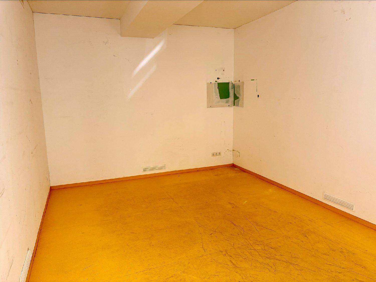 Leerer Raum mit weißen Wänden und hellem Laminatboden, der als Lager oder kleines Büro genutzt werden könnte.