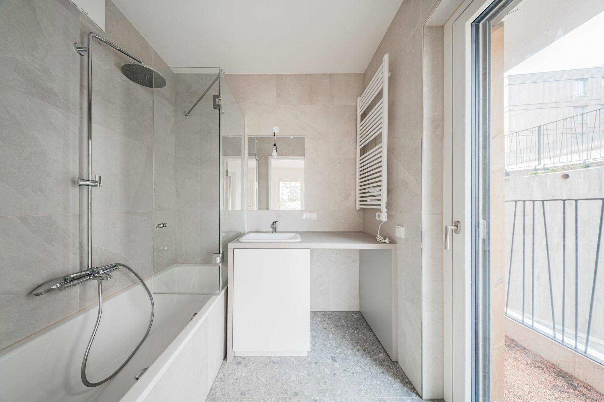 Modernes Badezimmer mit Badewanne, Regendusche, Einzelwaschbecken und beheiztem Handtuchhalter.