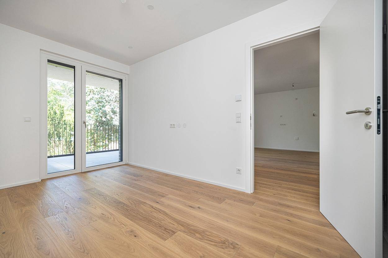 Lichtdurchflutetes Schlafzimmer mit Holzboden und direktem Zugang zu einem Außenbereich.