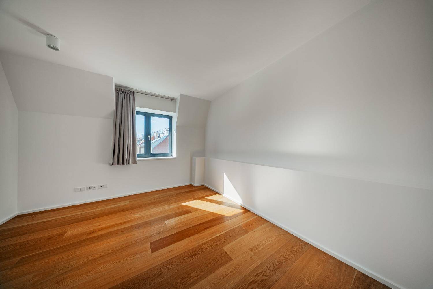 Leeres Schlafzimmer mit Holzboden und schrägen Wänden, das viel Potenzial für individuelle Gestaltung bietet.