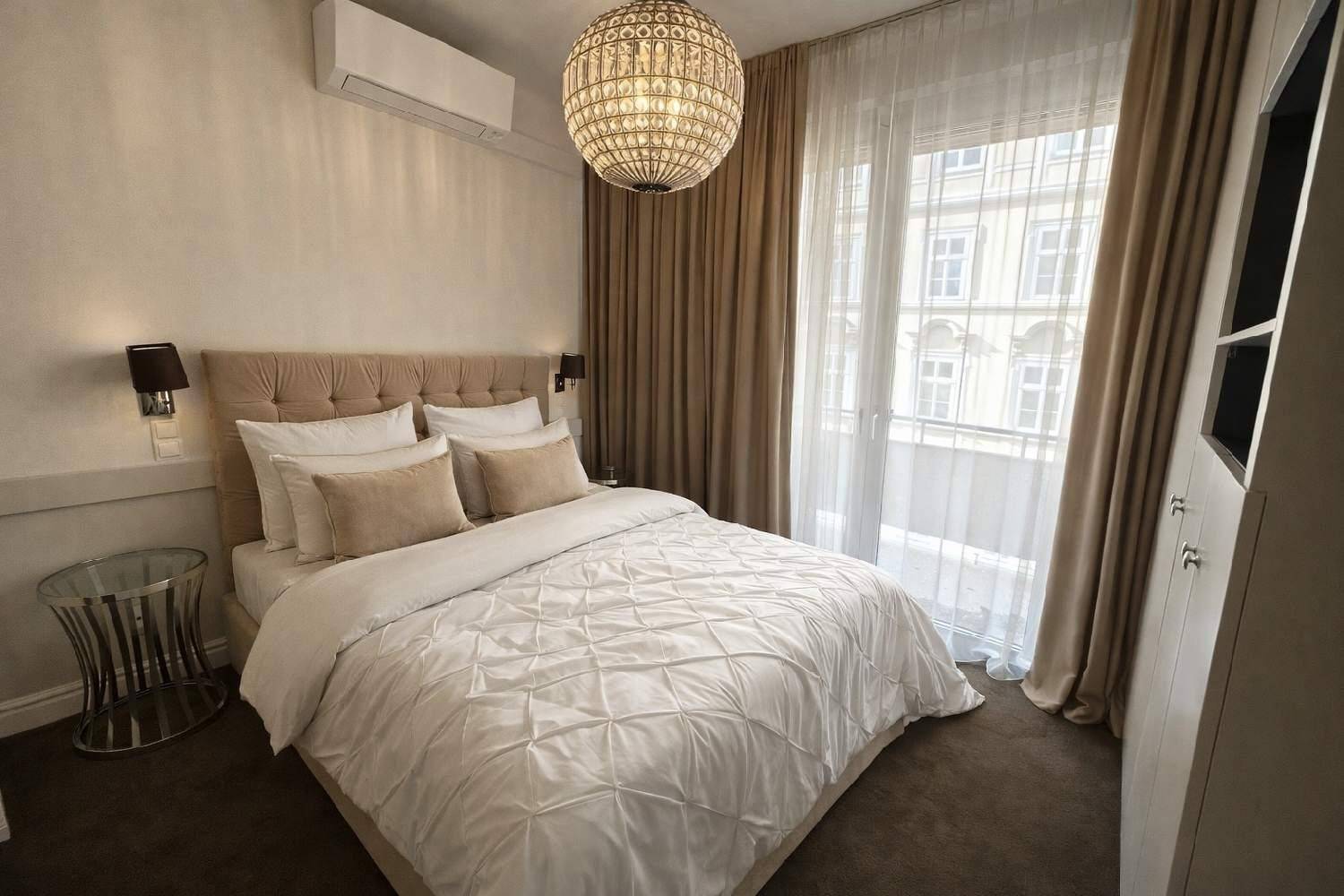 Helles Schlafzimmer mit Doppelbett, Nachttischen und Zugang zu einem französischen Balkon.
