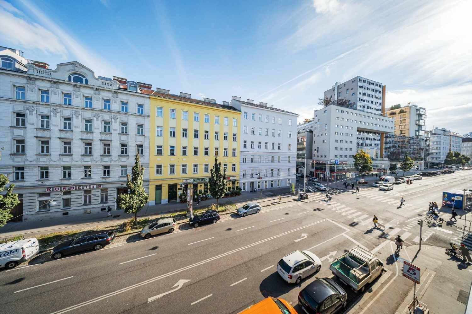 Panoramablick über eine städtische Straße mit vielfältiger Architektur und regem Verkehr.