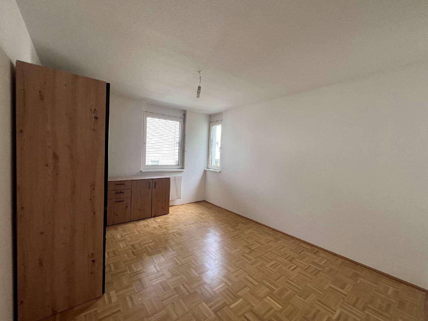 Helles Schlafzimmer mit Parkettboden, weißen Wänden und einem großen Holzschrank.